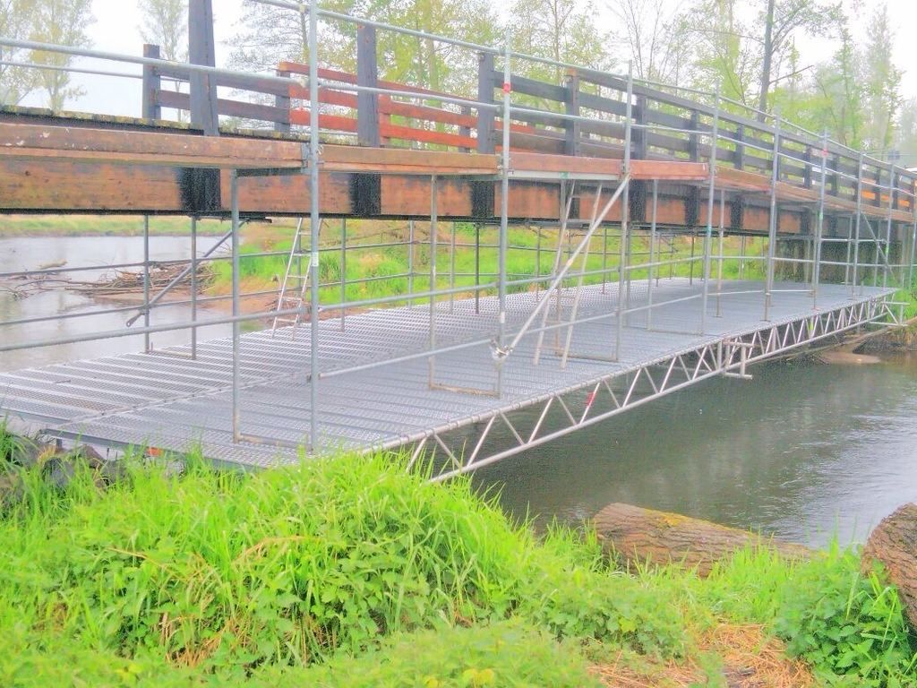Stahlbelag und Gitterträger eines Behelfsstegs neben einer hölzernen Brücke